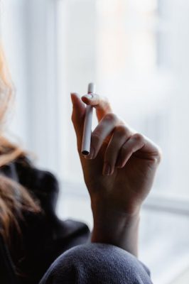 A person holding a Hitz disposable vape with visible vapor
