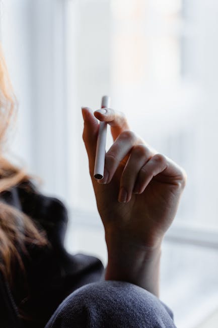 A person holding a Hitz disposable vape with visible vapor | hitzvape.com